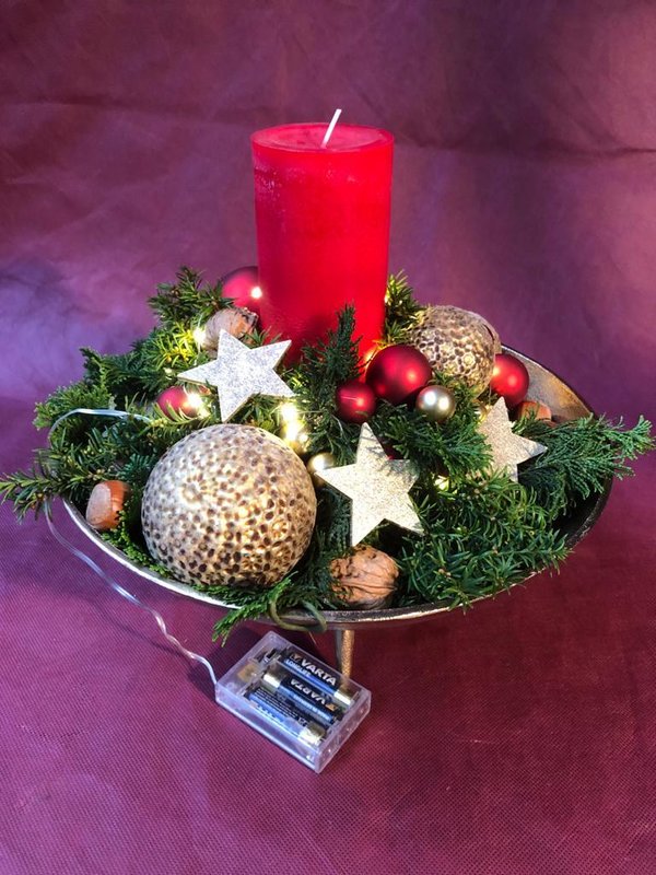 Adventsgesteck mit einer dicken Kerze und Lichterkette